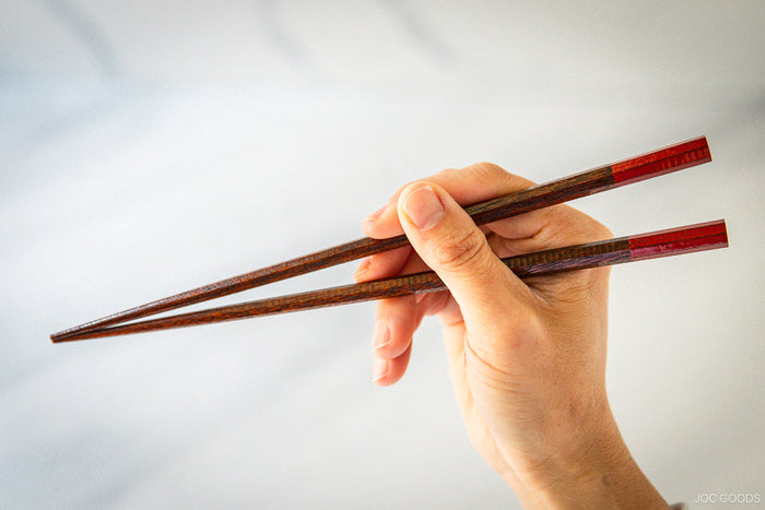 hand holding a pair of chopsticks