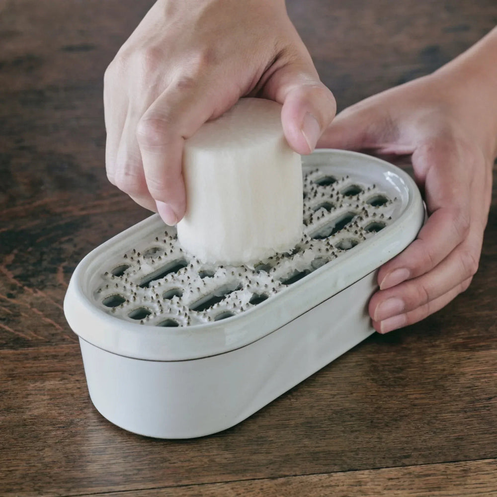 Ceramic Daikon Oroshi Grater with serving dish, shown grating daikon radish on a wooden table.