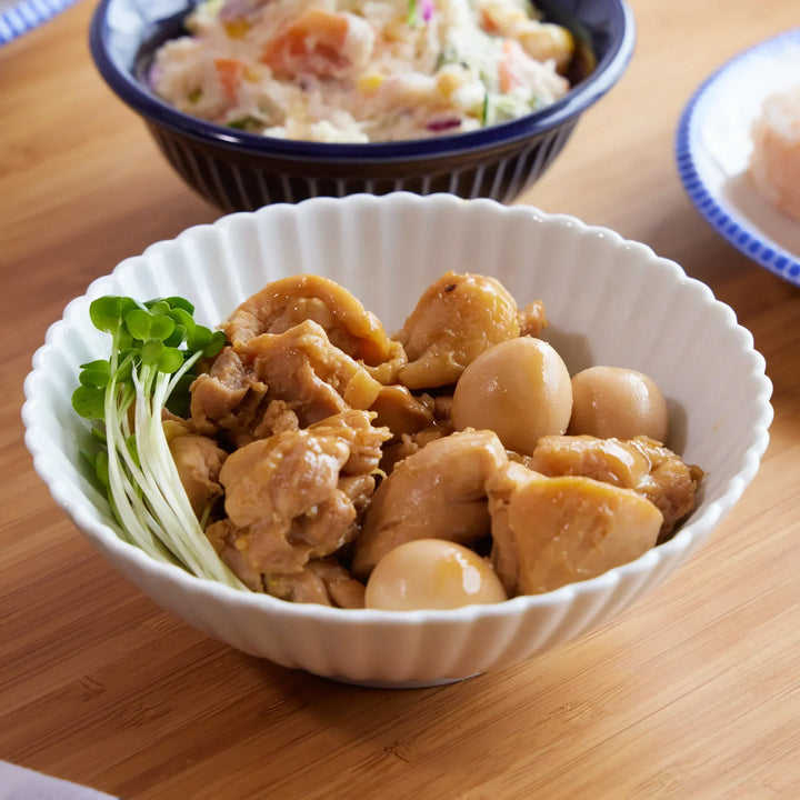 Braised chicken and quail eggs served in a white chrysanthemum-carved Japanese ceramic bowl.