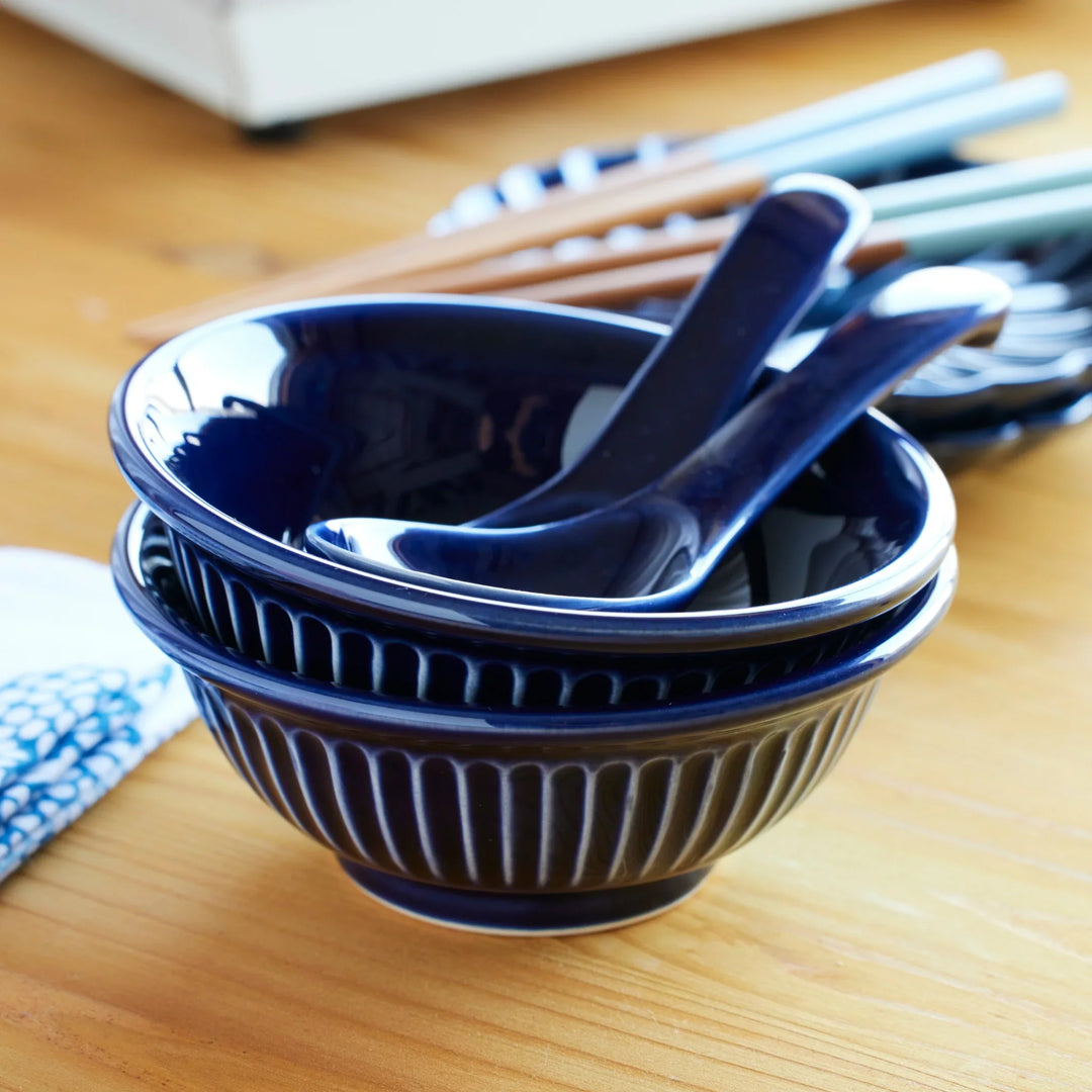 Stacked Japanese indigo blue ceramic ramen bowls with matching soup spoons, combining traditional design and modern elegance.