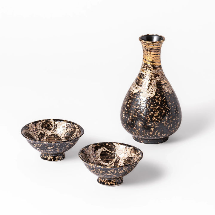 Dark brown and gold ceramic sake flask with two footed cups featuring a rustic textured glaze and elegant handcrafted finish.