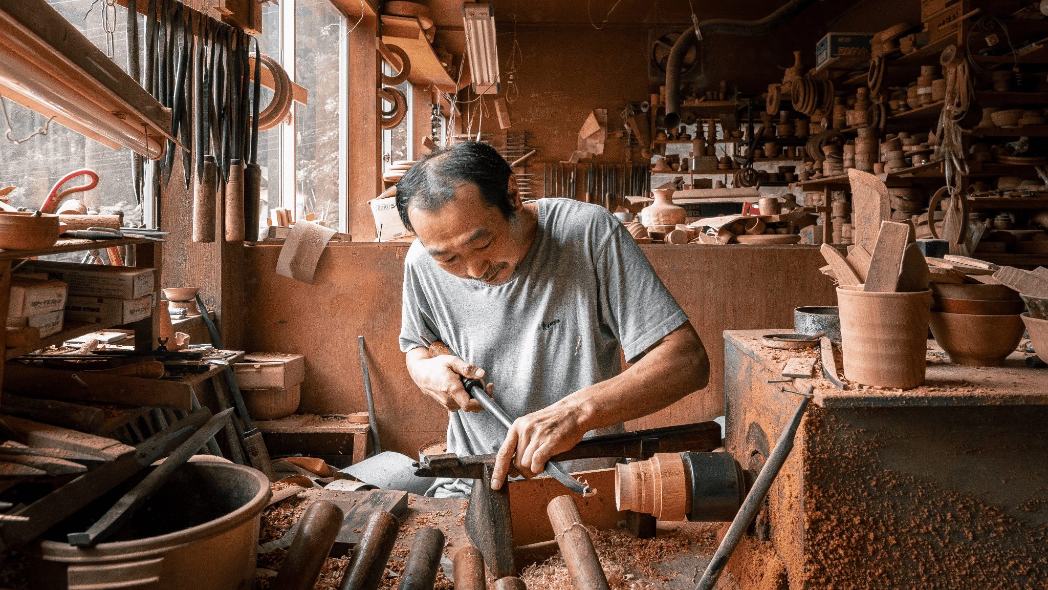 A skilled Japanese artisan carefully crafting wooden items, showcasing their dedication to traditional techniques.