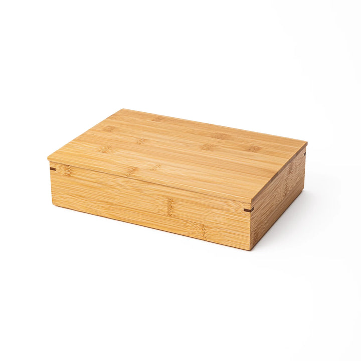 A closed rectangular bamboo bento box showing a smooth natural wood grain finish and a minimalist eco friendly design