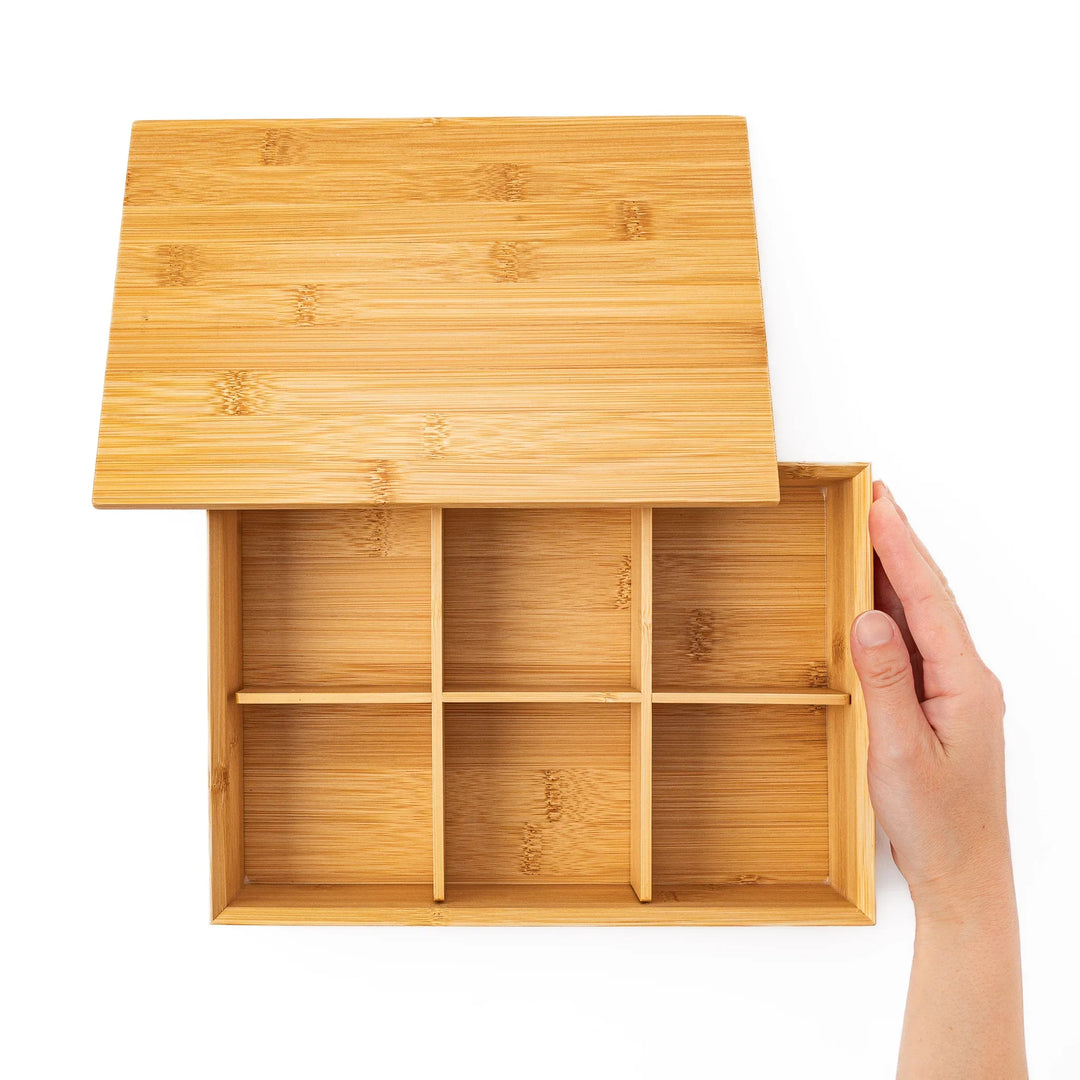 Top down view of an open bamboo bento box with a hand revealing six equal inner compartments for perfect food portioning