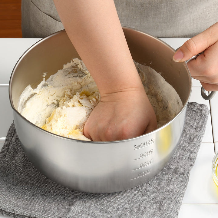 Person holding handle of an AUX Japanese Stainless Steel Mixing Bowl with Handle while kneading dough inside