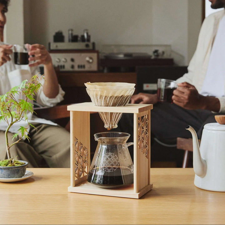 Showcasing aya asanoha wood coffee dripper set on wooden table with men drinking fresh coffee in cozy room cafe