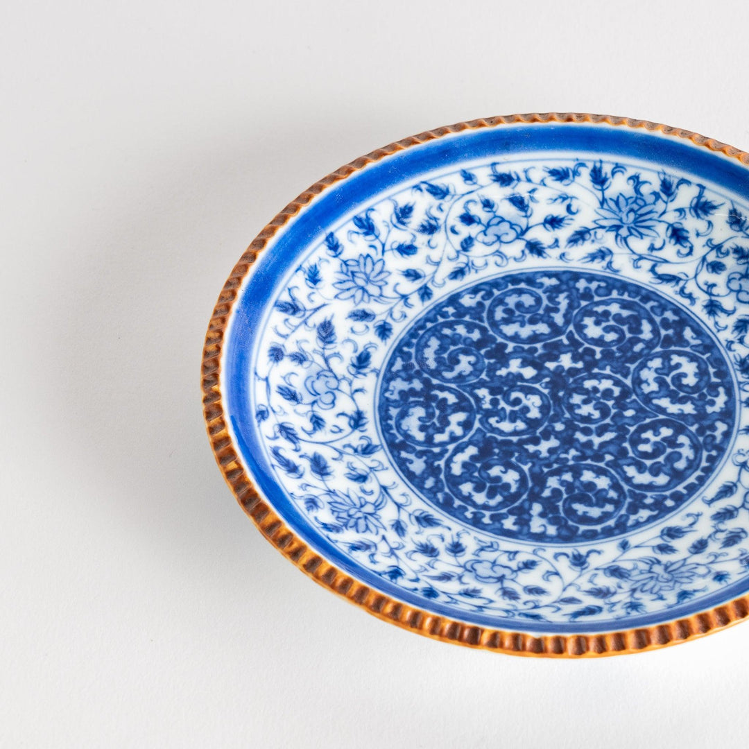 Ceramic plate with blue floral circular motif framed by copper textured rim for elegant Japanese dining.