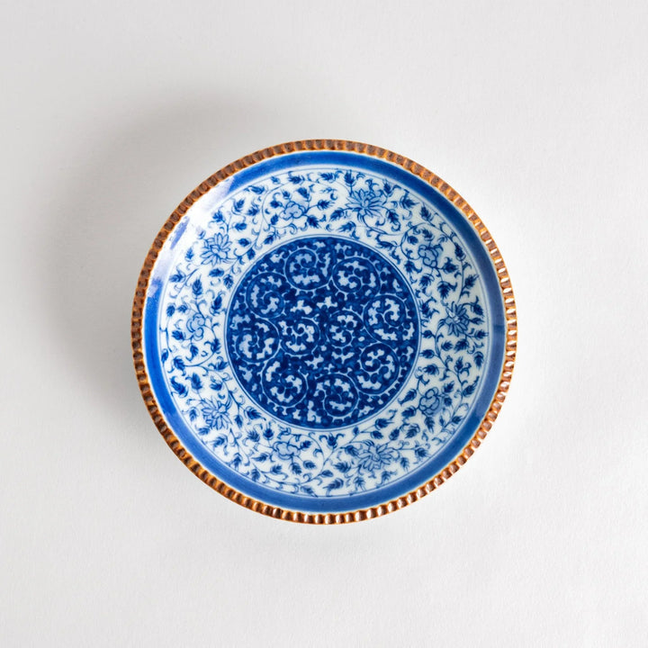 Ceramic plate with blue floral circular motif framed by copper textured rim for elegant Japanese dining.