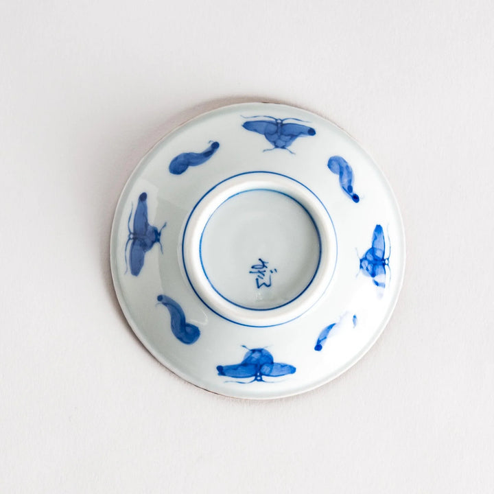 Small ceramic plate with intricate blue floral circular motif bordered by copper colored textured rim.