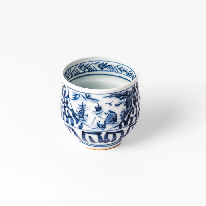Porcelain sake cup featuring intricate blue landscape and arabesque patterns with a traditional hand-painted indigo design.