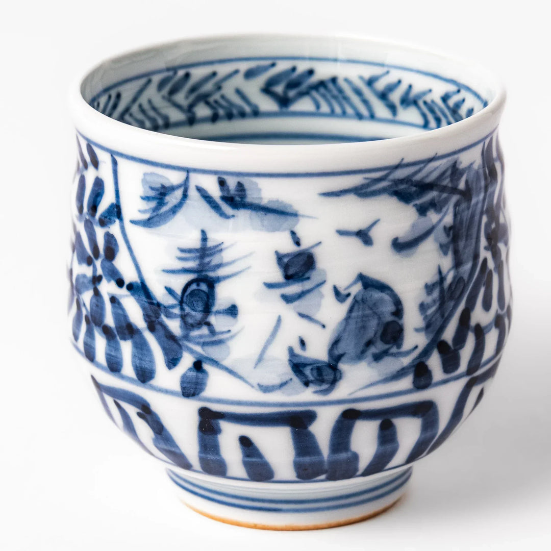 Porcelain sake cup featuring intricate blue landscape and arabesque patterns with a traditional hand-painted indigo design.