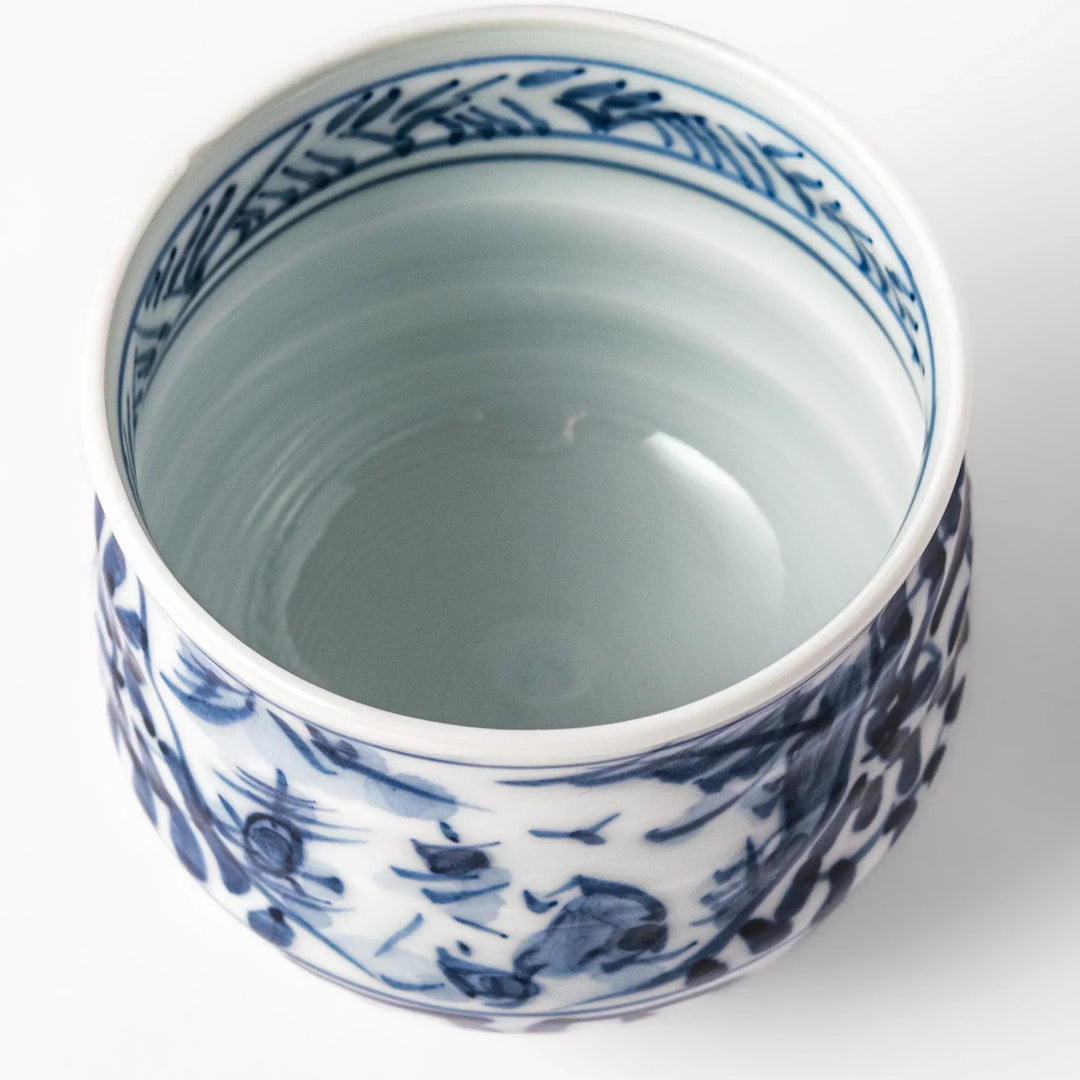 Porcelain sake cup featuring intricate blue landscape and arabesque patterns with a traditional hand-painted indigo design.