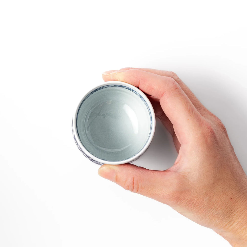 Porcelain sake cup featuring intricate blue landscape and arabesque patterns with a traditional hand-painted indigo design.