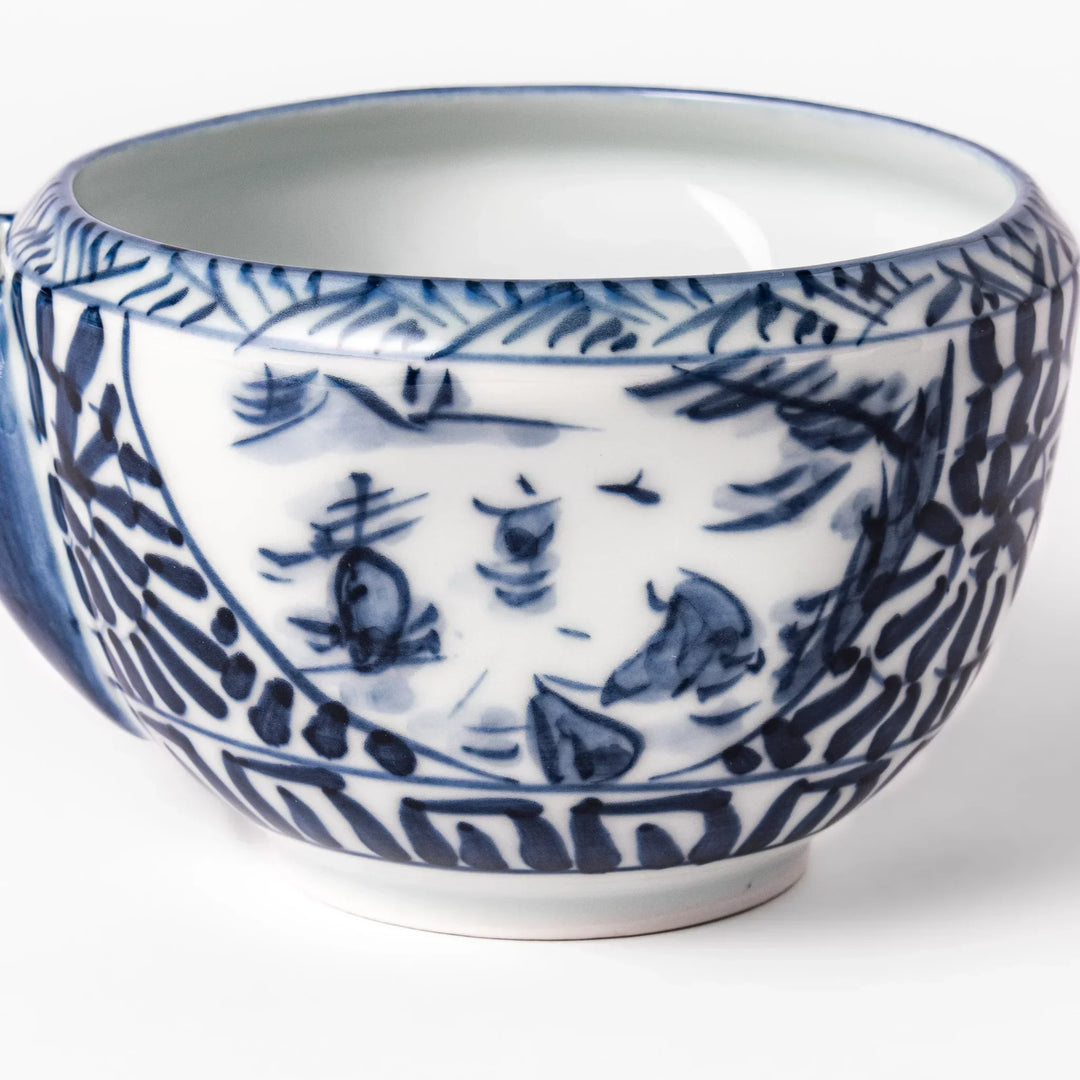 Porcelain sake pourer with spout featuring indigo landscape and arabesque motifs in Japanese tradition.