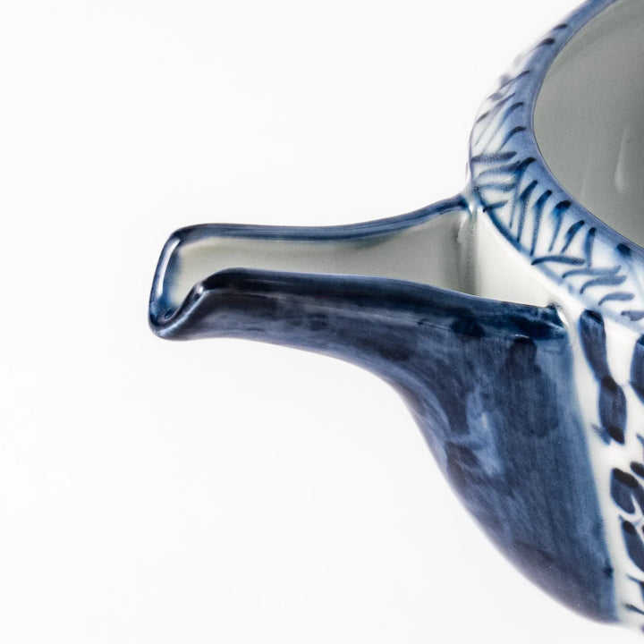 Porcelain sake pourer with spout featuring indigo landscape and arabesque motifs in Japanese tradition.