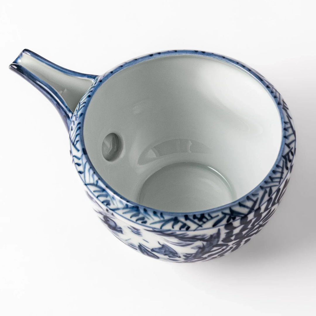 Porcelain sake pourer with spout featuring indigo landscape and arabesque motifs in Japanese tradition.