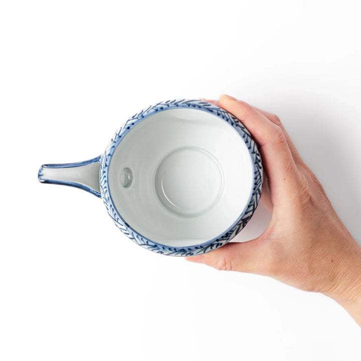Porcelain sake pourer with spout featuring indigo landscape and arabesque motifs in Japanese tradition.