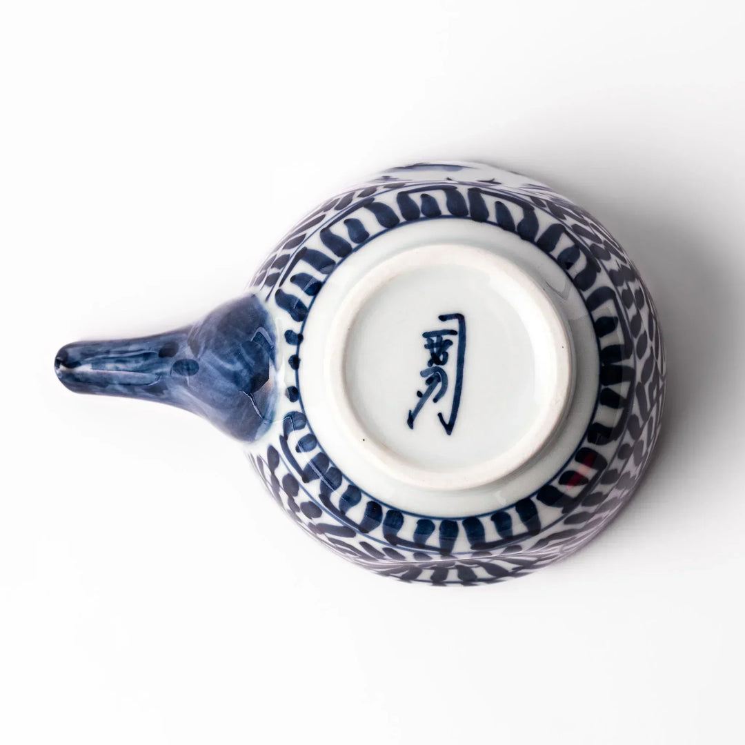 Porcelain sake pourer with spout featuring indigo landscape and arabesque motifs in Japanese tradition.