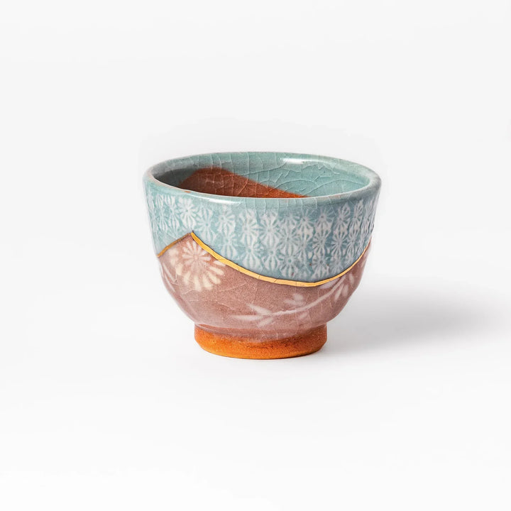 Turquoise crackle-glazed ceramic tea cup with floral patterns and earthy brown base, highlighting handcrafted beauty.