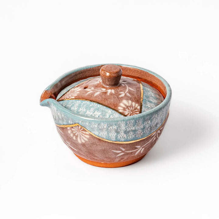 Turquoise crackle-glazed teapot with floral patterns and gold-accented spout, blending elegance and craftsmanship.