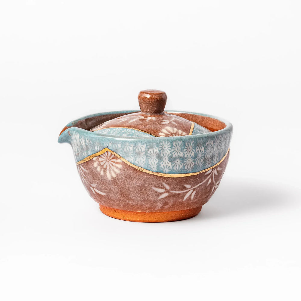 Turquoise crackle-glazed teapot with floral patterns and gold-accented spout, blending elegance and craftsmanship.