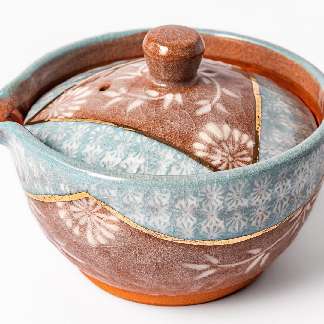 Turquoise crackle-glazed teapot with floral patterns and gold-accented spout, blending elegance and craftsmanship.