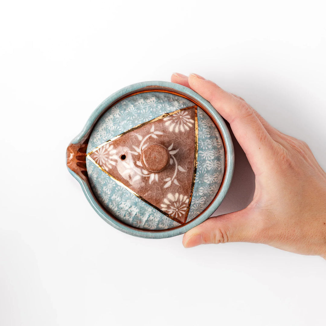 Turquoise crackle-glazed teapot with floral patterns and gold-accented spout, blending elegance and craftsmanship.