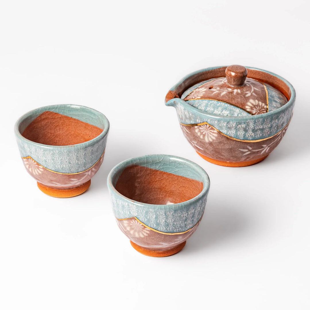Three piece Japanese ceramic tea set with turquoise crackle glaze floral patterns teapot and matching cups.