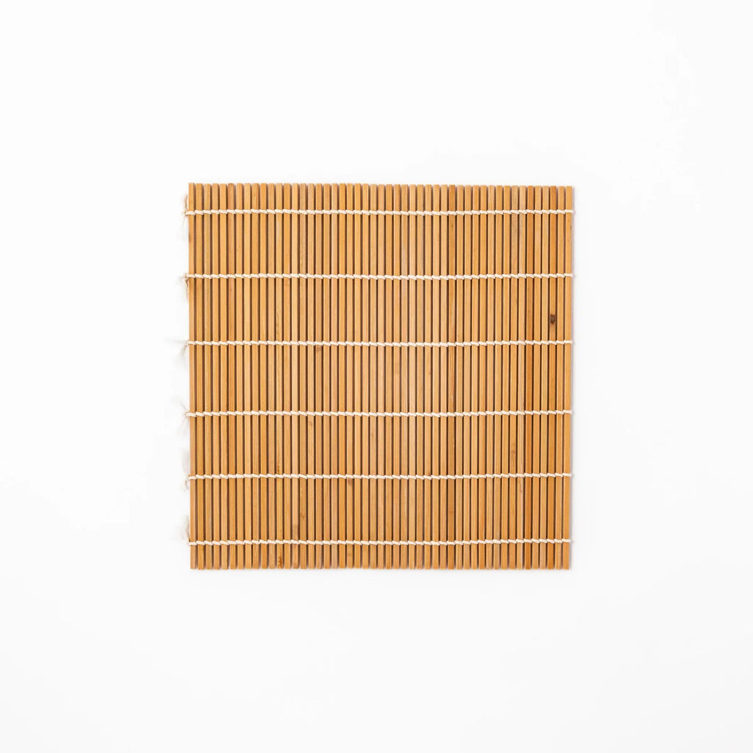 Traditional bamboo sushi rolling mat with uniform slats and white cotton string for home sushi making.
