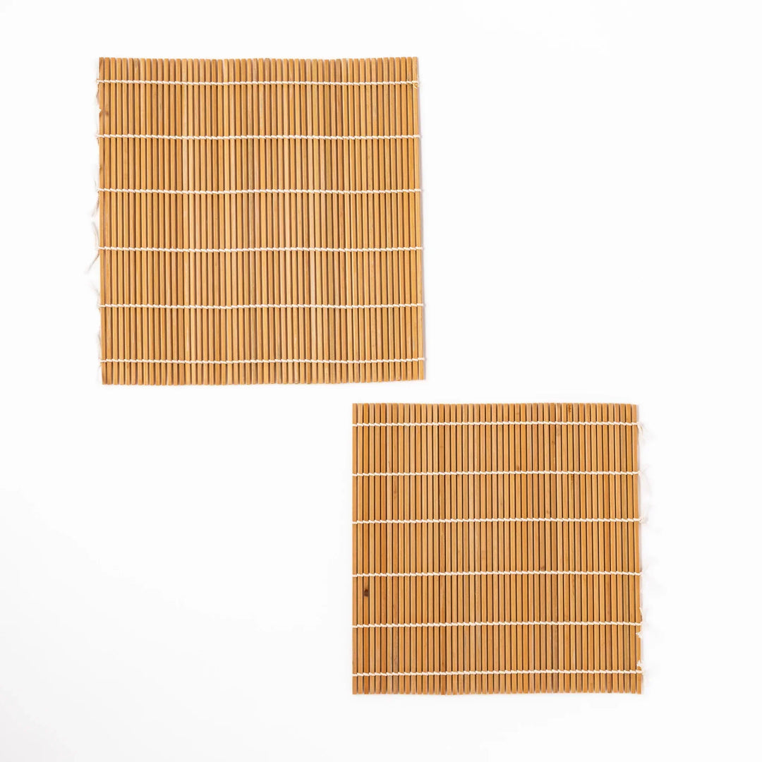 Two bamboo sushi rolling mats with tight slats and white cotton ties for crafting precise sushi rolls.
