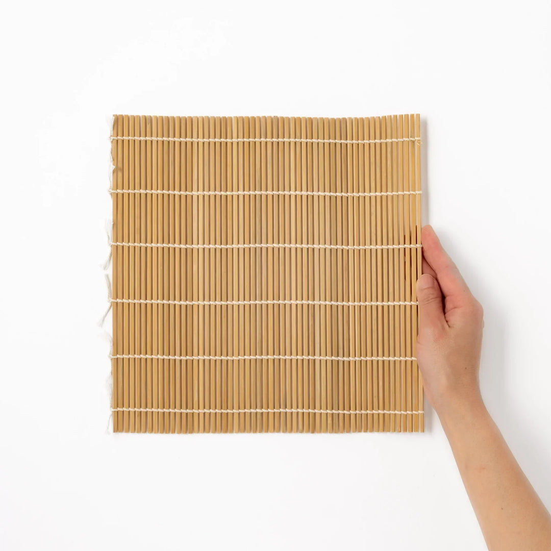 Bamboo sushi rolling mat with smooth even slats and white cotton string for shaping homemade sushi rolls.