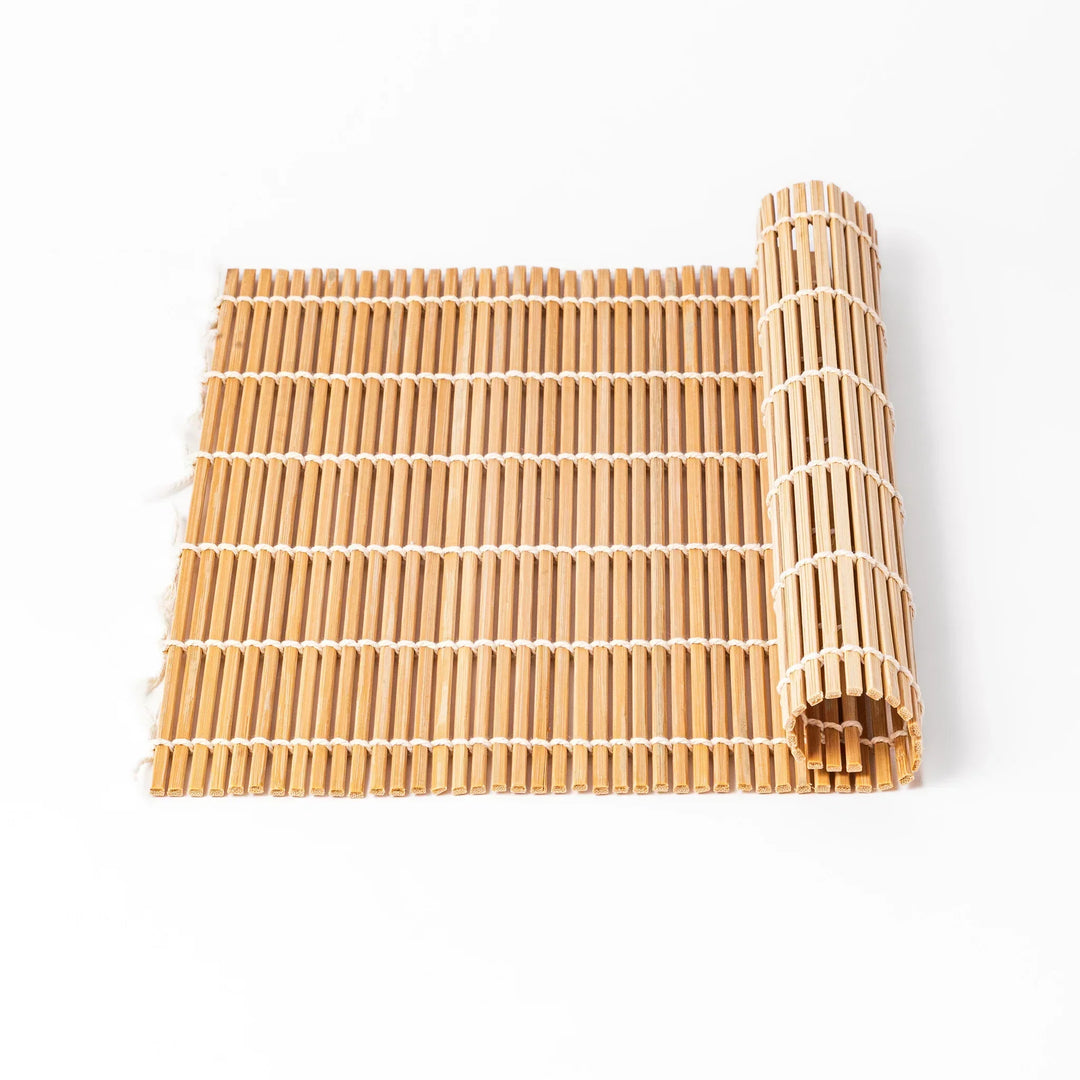 Bamboo sushi rolling mat with smooth even slats and white cotton string for shaping homemade sushi rolls.