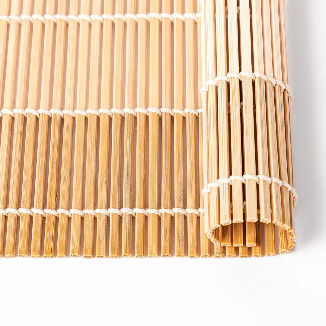 Bamboo sushi rolling mat with smooth even slats and white cotton string for shaping homemade sushi rolls.
