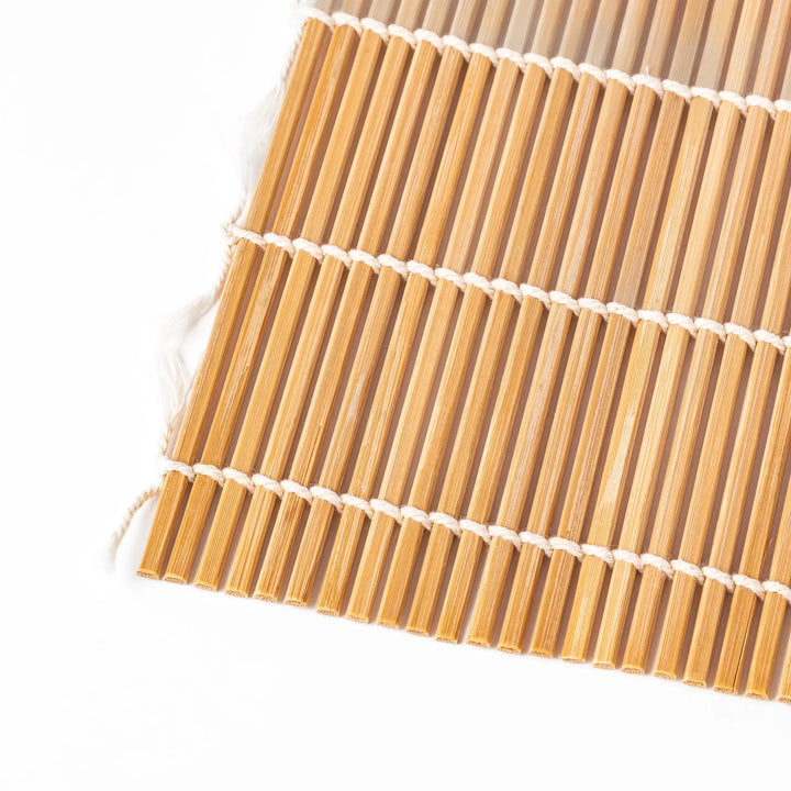 Bamboo sushi rolling mat with smooth even slats and white cotton string for shaping homemade sushi rolls.