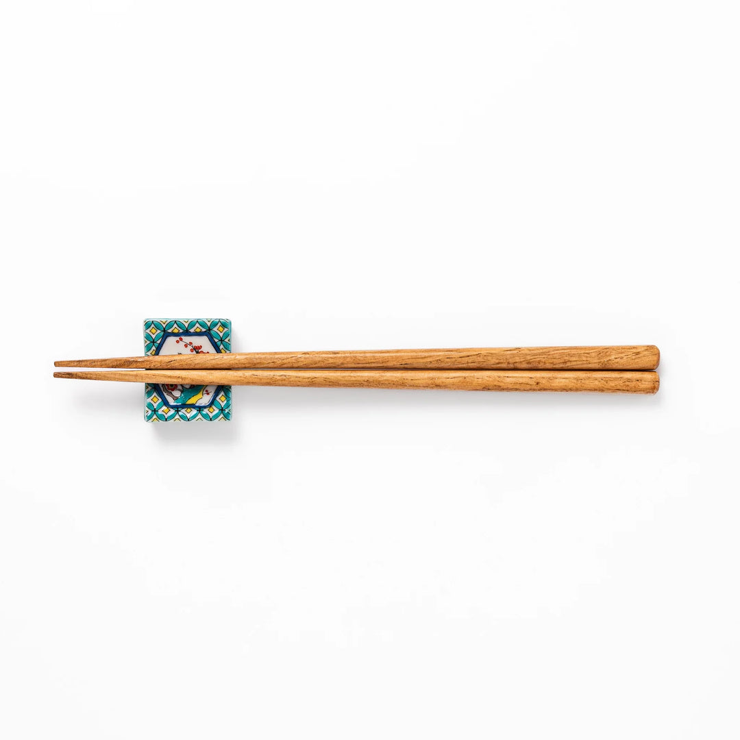 Rectangular Japanese ceramic chopstick rest with turquoise border and central motif of bird on plum blossoms in vivid colors.