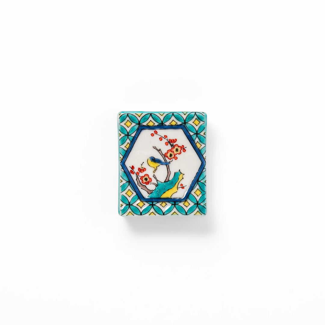 Rectangular Japanese ceramic chopstick rest with turquoise border and central motif of bird on plum blossoms in vivid colors.
