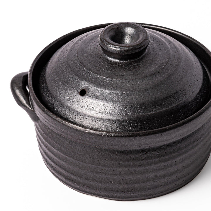 Black clay donabe with induction-compatible design, featuring double lid and side handles, ideal for cooking 2 cups of rice.