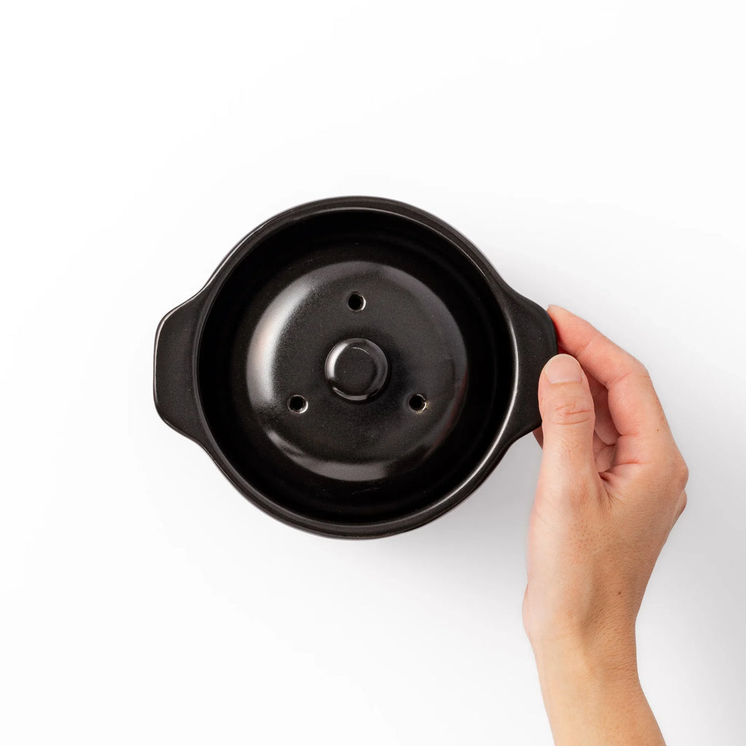 Black ceramic microwave rice cooker with double lid and handles for convenient cooking and table serving.