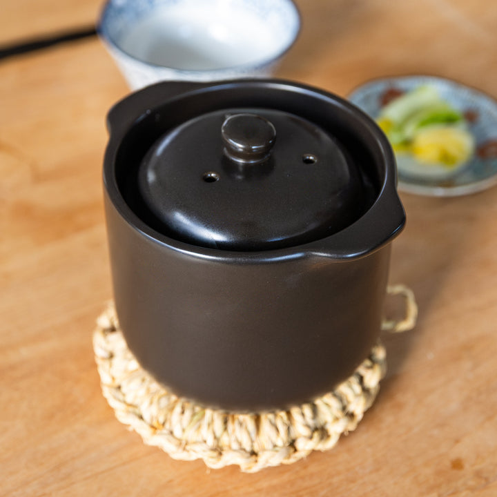 Black microwave rice cooker with double lid placed on table ready to serve Japanese rice