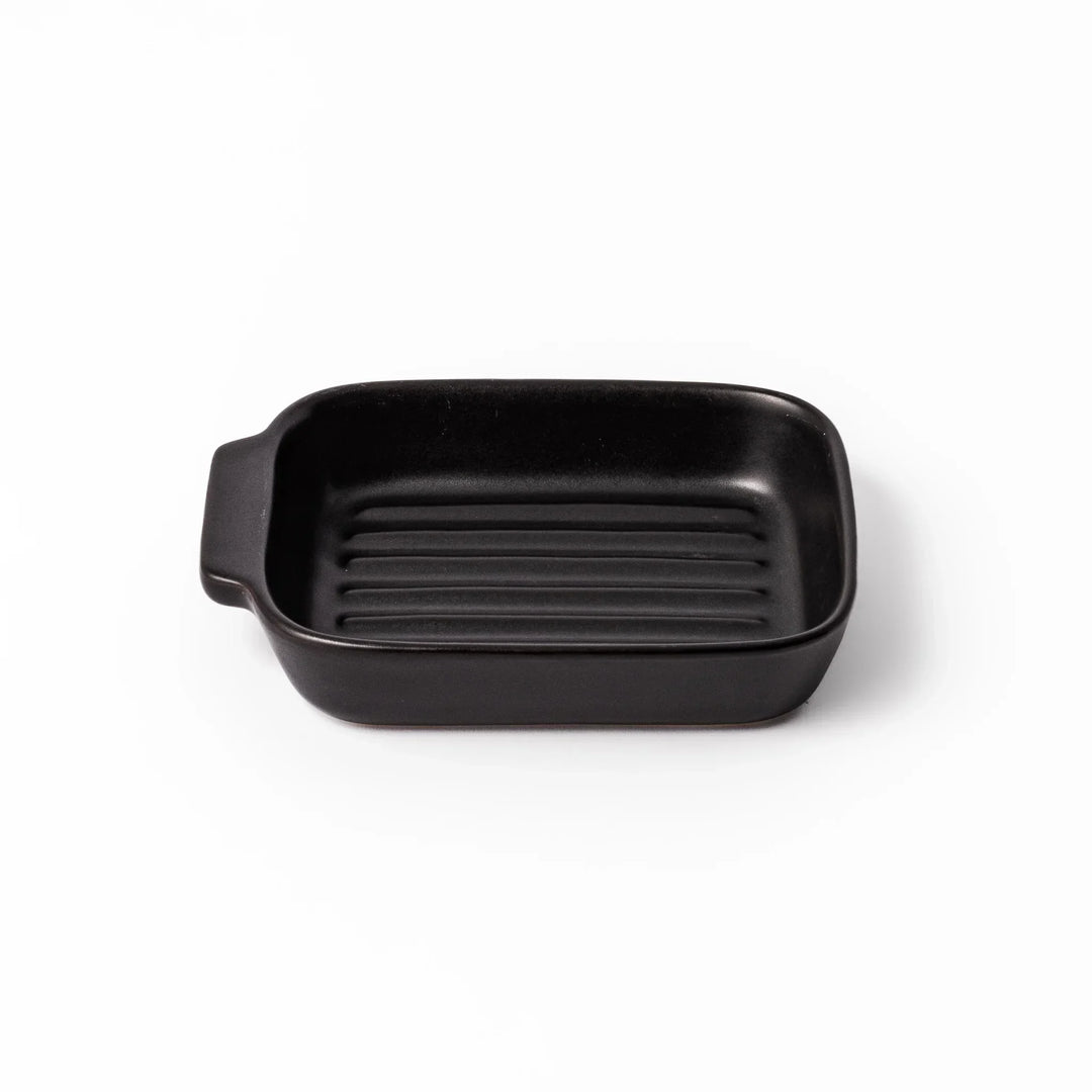 Rectangular black ceramic baking dish with ridged base and handle for oven use and versatile serving.