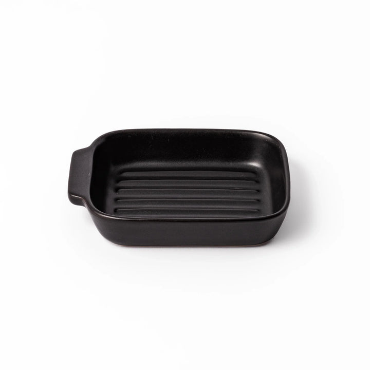 Rectangular black ceramic baking dish with ridged base and handle for oven use and versatile serving.