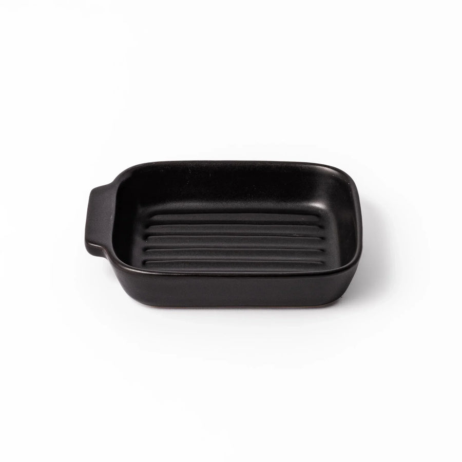 Rectangular black ceramic baking dish with ridged base and handle for oven use and versatile serving.