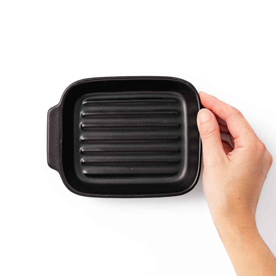 Rectangular black ceramic baking dish with ridged base and handle for oven use and versatile serving.