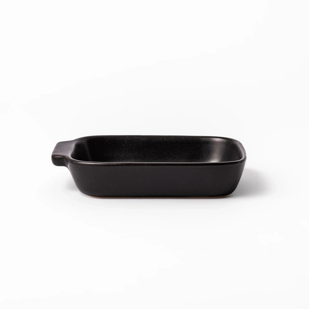 Rectangular black ceramic baking dish with ridged base and handle for oven use and versatile serving.