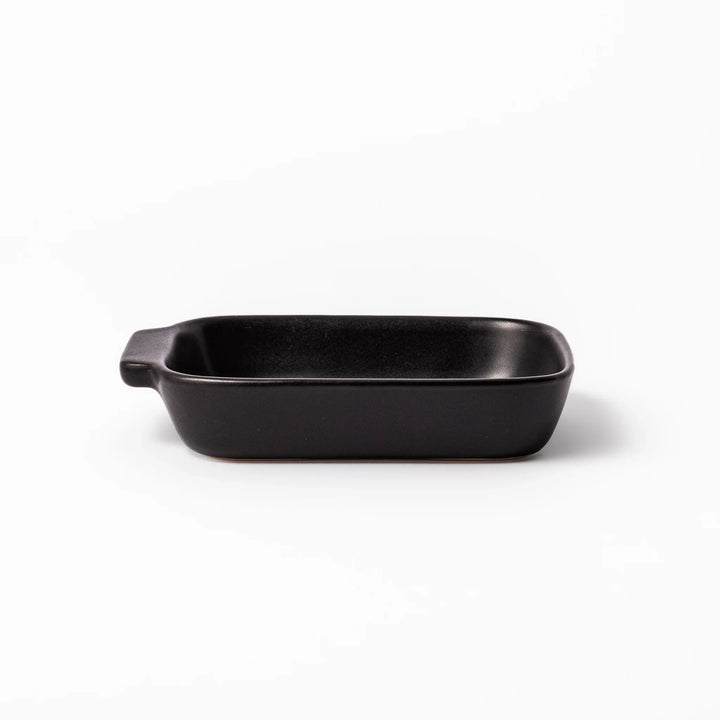 Rectangular black ceramic baking dish with ridged base and handle for oven use and versatile serving.