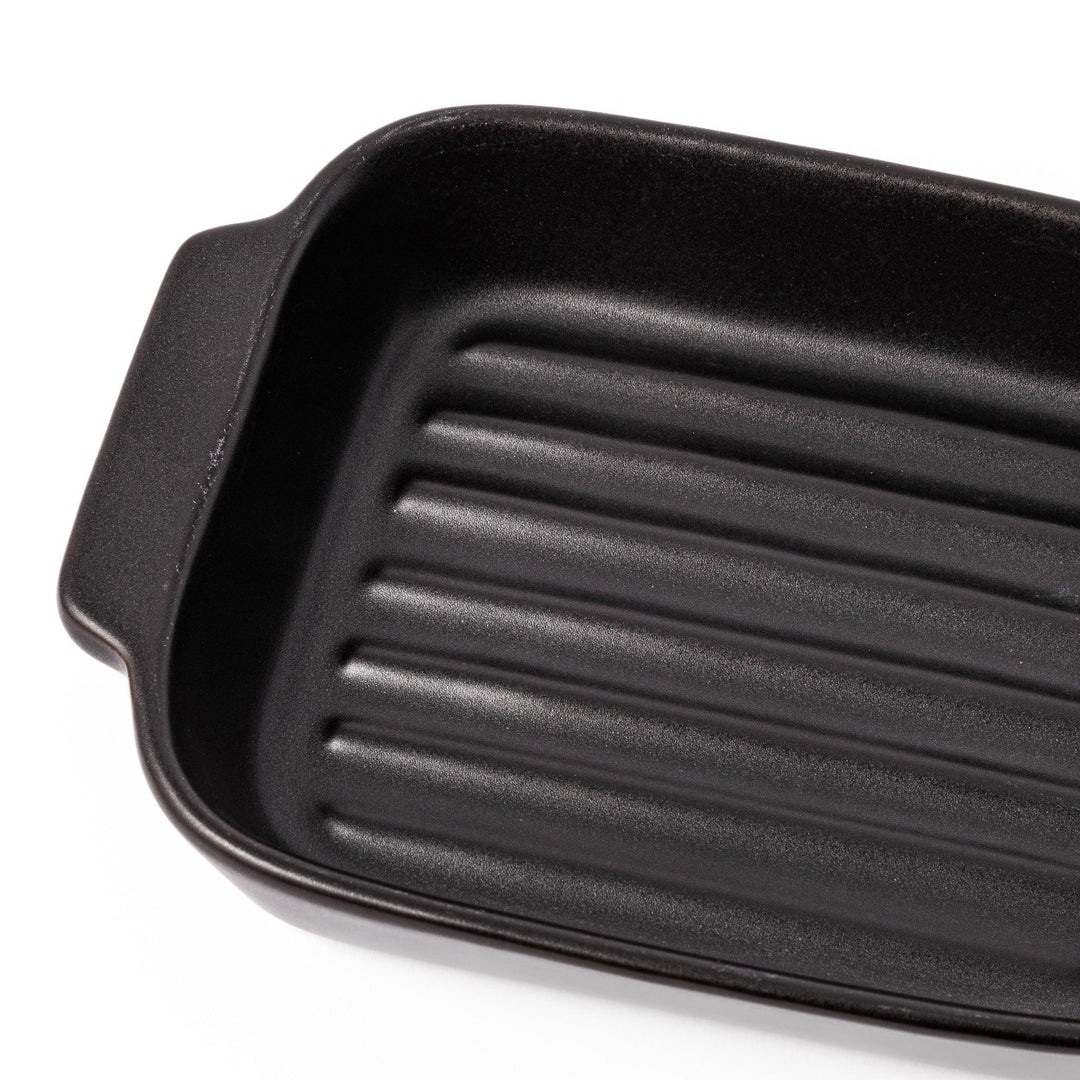 Rectangular black ceramic baking dish with ridged base and handle for oven use and versatile serving.
