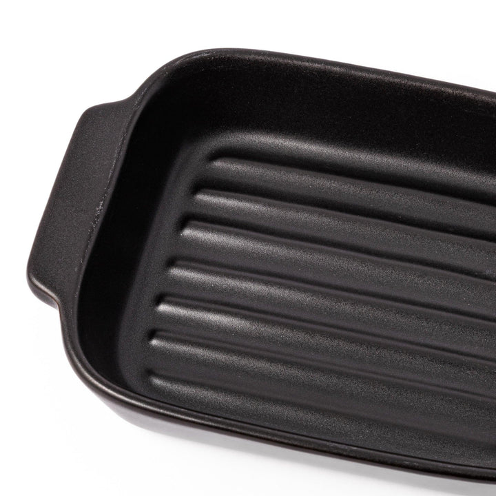 Rectangular black ceramic baking dish with ridged base and handle for oven use and versatile serving.