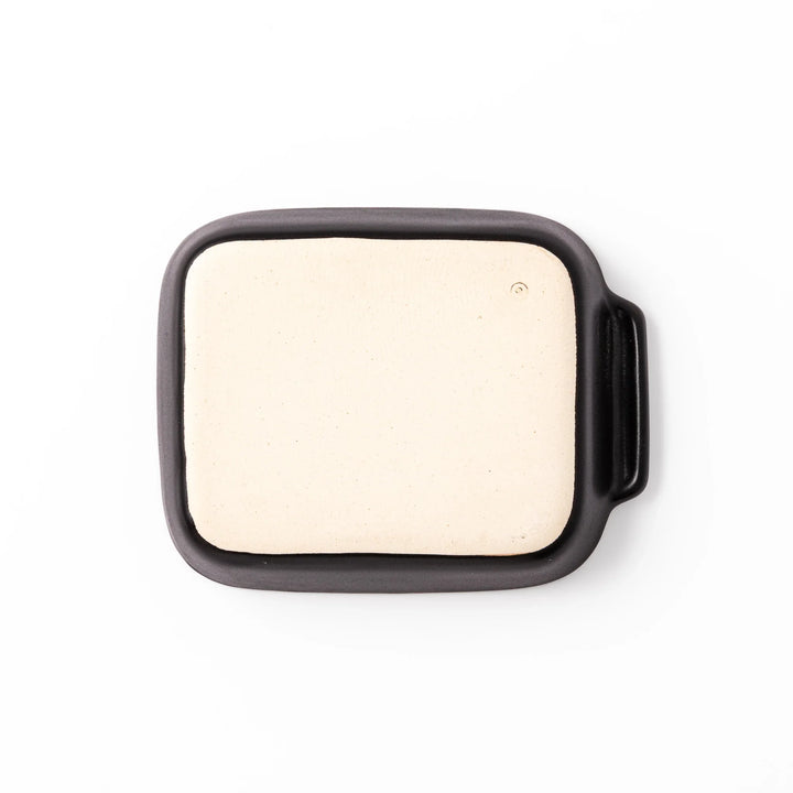 Rectangular black ceramic baking dish with ridged base and handle for oven use and versatile serving.