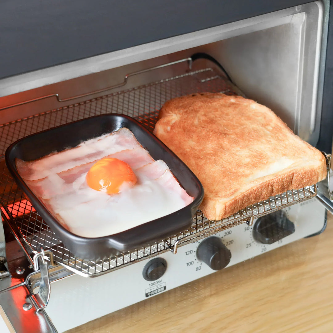 Rectangular black ceramic baking dish with ridged base and handle for oven use and versatile serving.