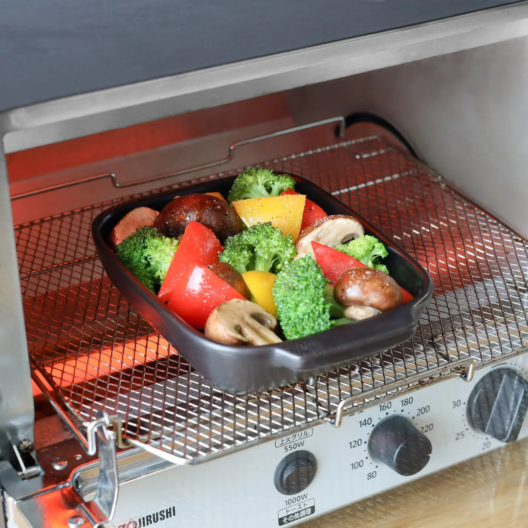 Rectangular black ceramic baking dish with ridged base and handle for oven use and versatile serving.
